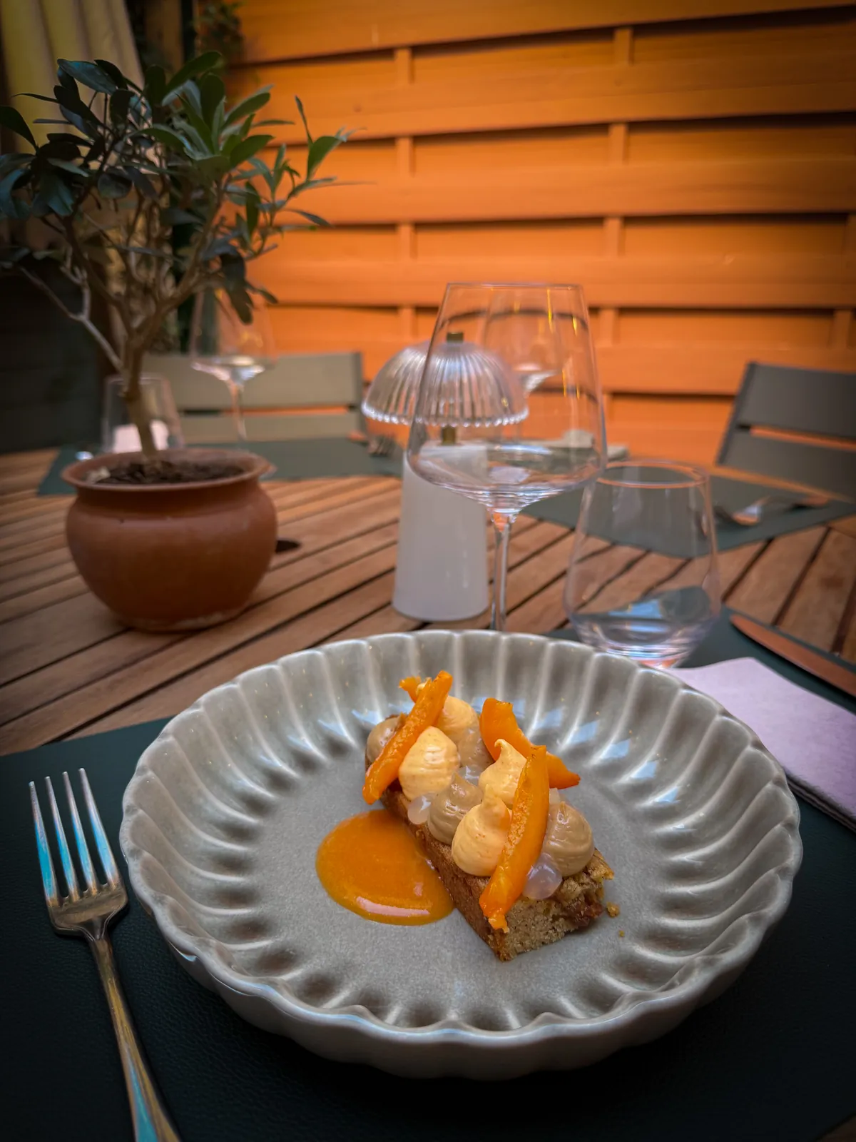Dessert aux fruits orangés et crème servi sur une table de la terrasse de Cachette